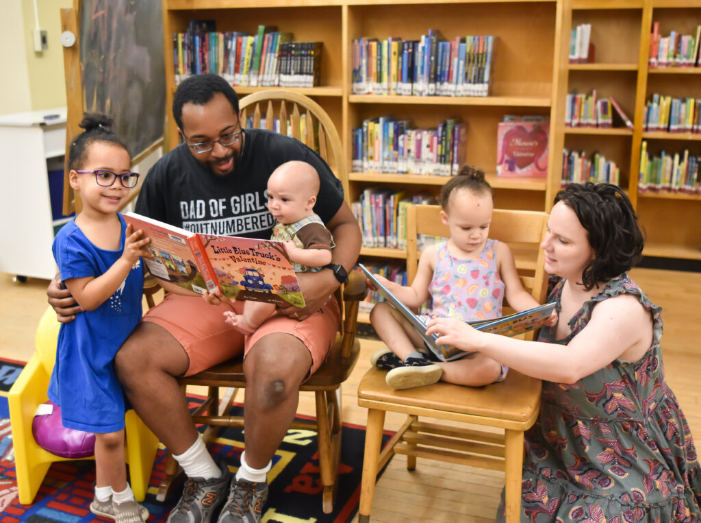 A family with young kids reads books in a library.